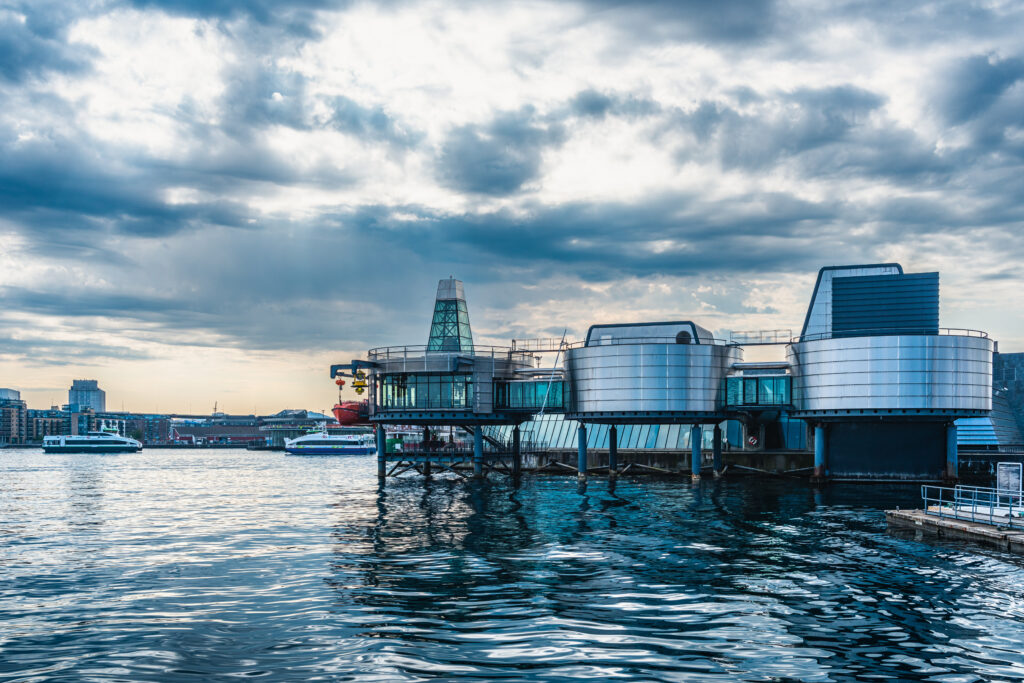 View of the Norwegian Petroleum Museum in Stavanger, Norway, featuring modern architecture against a dramatic cloudy sky, reflecting on the waterfront.