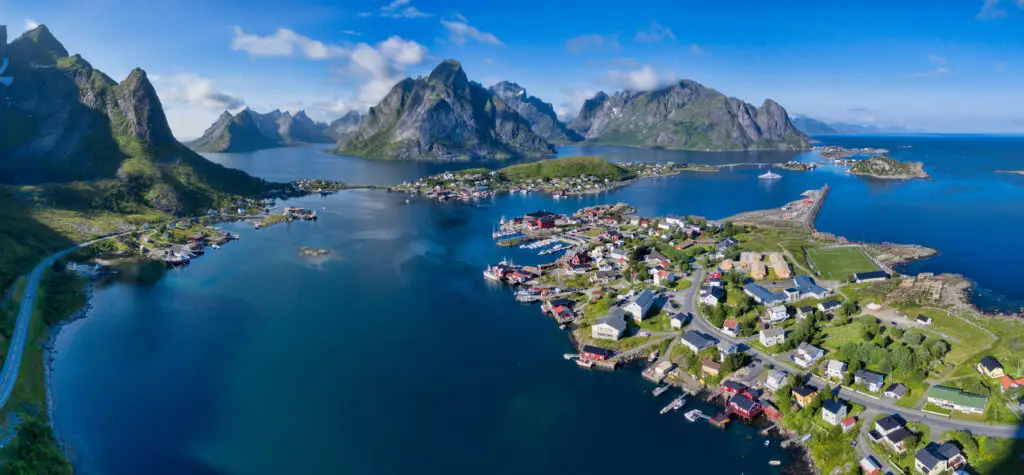 Aerial view of Reine in the Lofoten Islands, Norway, showcasing the dramatic mountain landscapes and picturesque fishing village with its traditional red rorbuer cabins.