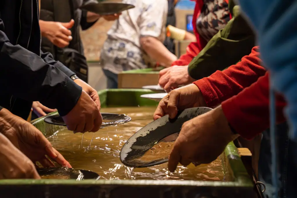 Tourists engaging in gold panning at Tankavaara Gold Village in Finland, exploring a unique tourist attraction in Scandinavia
